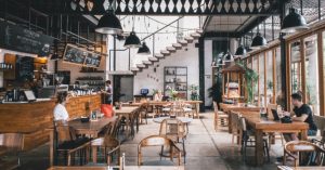 Image of a restaurant/coffee shop with a lot of empty tables and only a few customers.