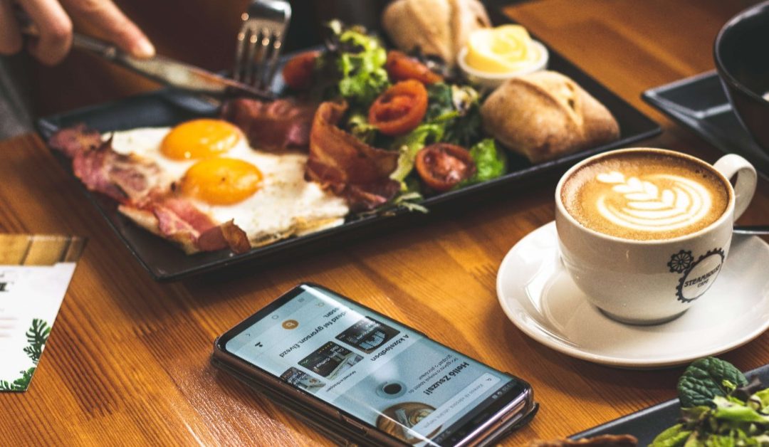 Photo of beautiful arrangement of food at a restaurant with a phone sitting on the table.