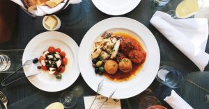 Image of a delicious meal of food and drinks on white plates on a dark table.